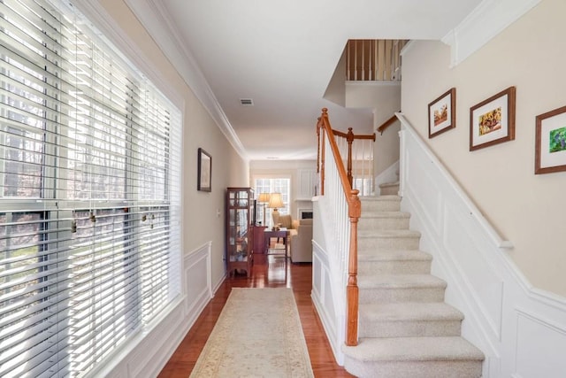 stairway with ornamental molding and hardwood / wood-style floors