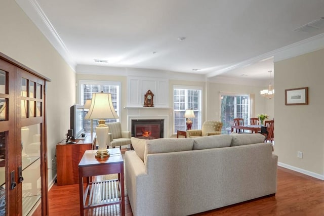 living room with an inviting chandelier, crown molding, and hardwood / wood-style flooring