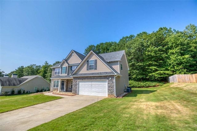 view of front of house featuring a front yard, fence, a garage, stone siding, and driveway