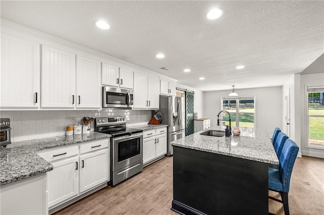 137 Evergreen Ridge Ct, Statham, GA 30666 - kitchen with stainless steel appliances, a sink, backsplash, a breakfast bar, and white cabinets