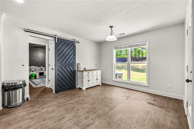 137 Evergreen Ridge Ct, Statham, GA 30666 - unfurnished room with a barn door, wood finished floors, a textured ceiling, and baseboards