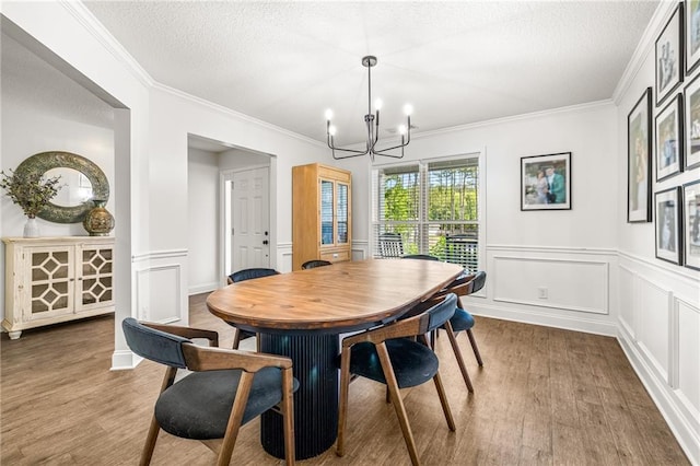 137 Evergreen Ridge Ct, Statham, GA 30666 - dining room featuring wood finished floors, a chandelier, ornamental molding, a textured ceiling, and wainscoting