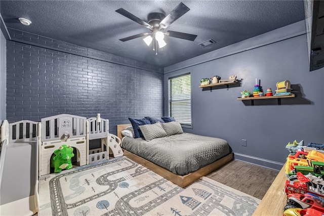 137 Evergreen Ridge Ct, Statham, GA 30666 - bedroom with wood finished floors, brick wall, a textured ceiling, a ceiling fan, and baseboards