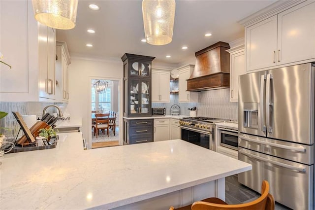 kitchen featuring pendant lighting, premium range hood, kitchen peninsula, and appliances with stainless steel finishes