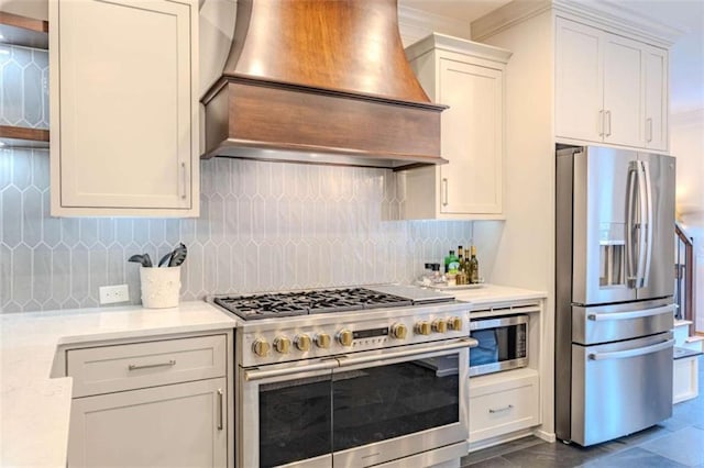 kitchen with stainless steel appliances, tasteful backsplash, light stone counters, custom range hood, and white cabinets