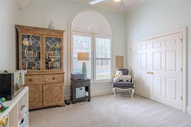 living area with ceiling fan, light colored carpet, and ornamental molding