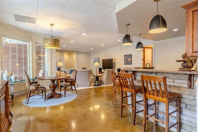 dining room featuring concrete flooring and a drop ceiling