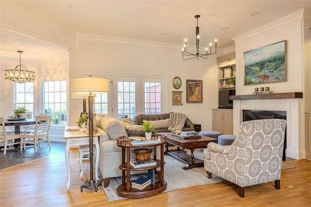 living room featuring crown molding, light hardwood / wood-style floors, and a notable chandelier