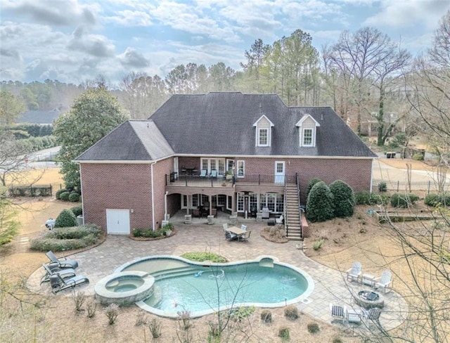 rear view of house featuring an outdoor fire pit, a pool with hot tub, and a patio area