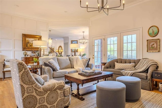 living room with crown molding, a chandelier, and light hardwood / wood-style floors