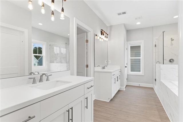 bathroom featuring hardwood / wood-style flooring, shower with separate bathtub, and dual bowl vanity