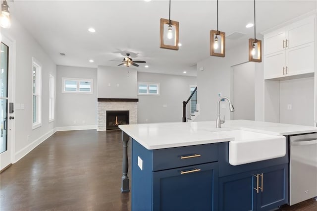 kitchen with sink, dark hardwood / wood-style flooring, a fireplace, dishwasher, and ceiling fan