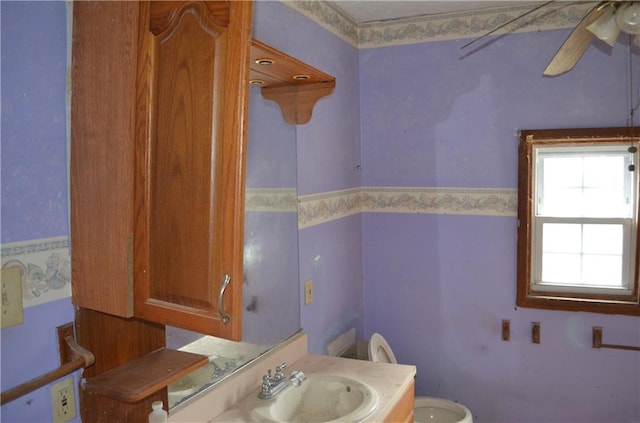 bathroom featuring a wealth of natural light, toilet, sink, and ceiling fan