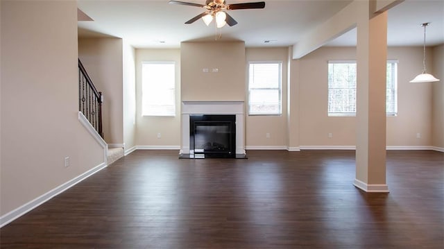 unfurnished living room featuring a ceiling fan, dark wood finished floors, baseboards, and stairs