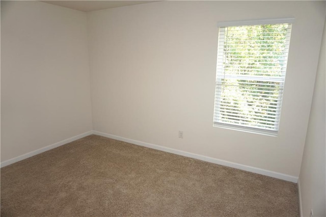 unfurnished room with carpet and baseboards