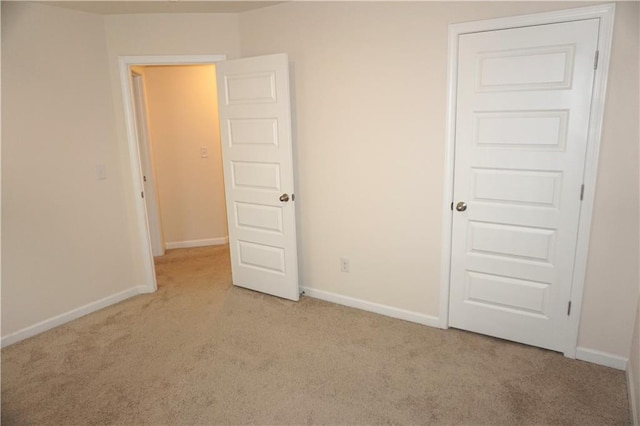 unfurnished bedroom featuring baseboards and light colored carpet