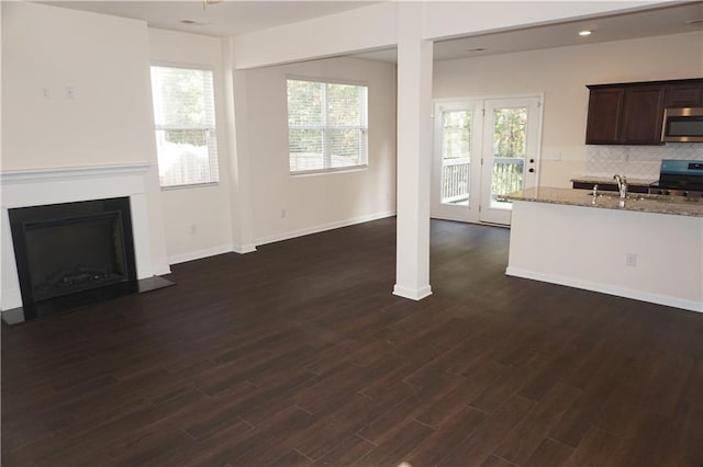 unfurnished living room featuring a sink, a fireplace with flush hearth, plenty of natural light, and dark wood finished floors