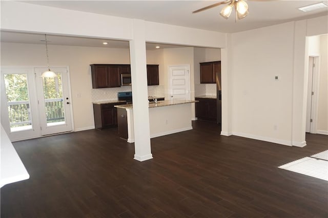 kitchen with dark wood-type flooring, stainless steel microwave, dark brown cabinets, and tasteful backsplash