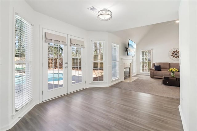 doorway with a high end fireplace, french doors, vaulted ceiling, and wood finished floors