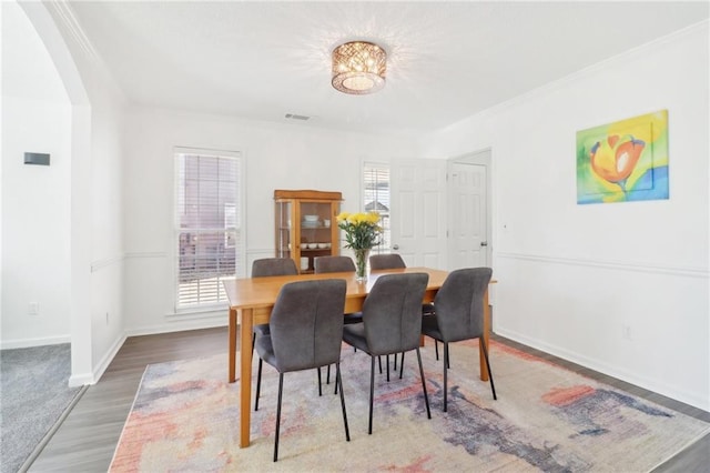 dining room with visible vents, crown molding, baseboards, and wood finished floors