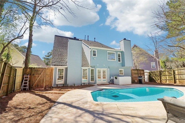 back of house featuring a fenced backyard, a chimney, a gate, french doors, and a patio area