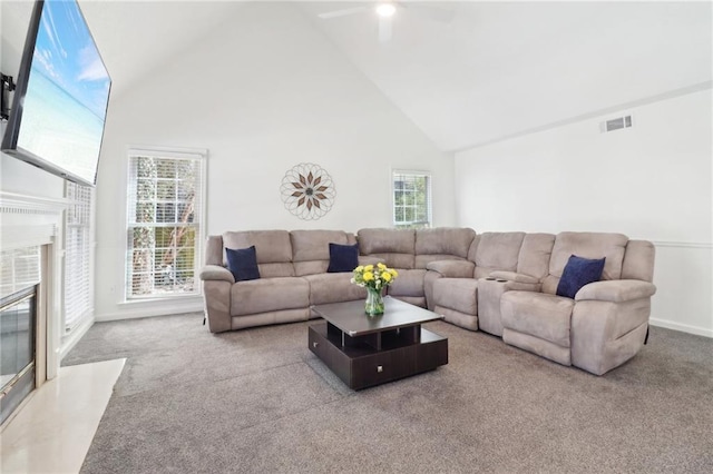 carpeted living area featuring visible vents, high vaulted ceiling, a high end fireplace, and baseboards