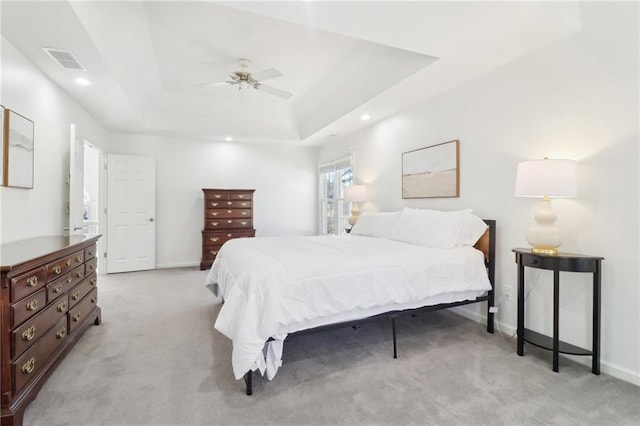 bedroom with a raised ceiling, visible vents, light carpet, and baseboards