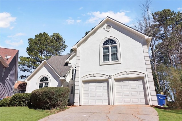 view of front of property with driveway, an attached garage, a front yard, and stucco siding