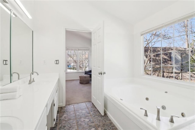 bathroom with double vanity, lofted ceiling, a sink, and a whirlpool tub