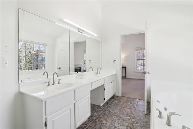 bathroom featuring double vanity, a tub to relax in, and a sink