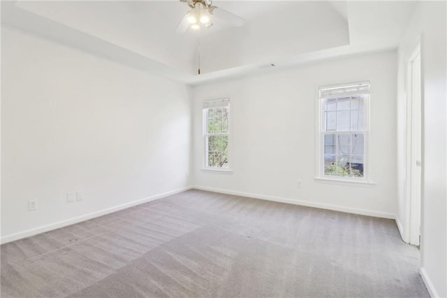 empty room with carpet floors, baseboards, and a raised ceiling