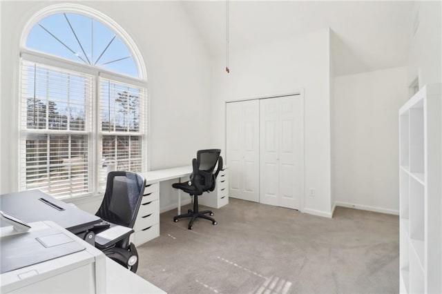 carpeted office featuring high vaulted ceiling and baseboards