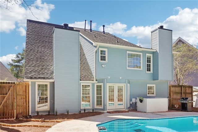 back of property with french doors, a chimney, fence, and a fenced in pool