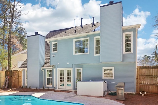 back of house featuring fence, french doors, a fenced in pool, a chimney, and a patio area