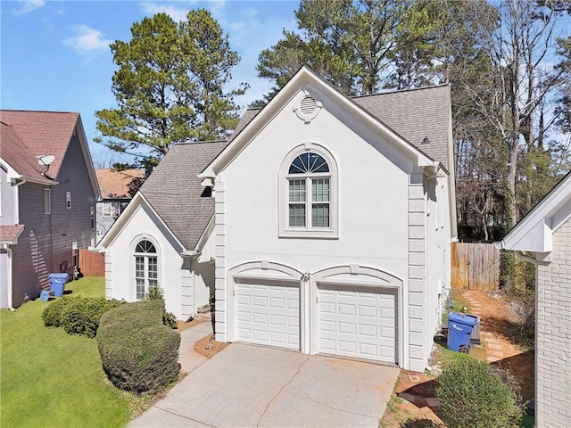 view of front of property with a shingled roof, fence, concrete driveway, and stucco siding