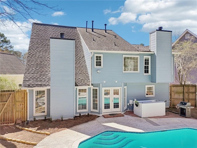 rear view of house with a fenced in pool, a patio, a chimney, fence, and french doors