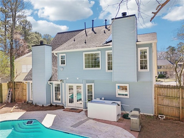 rear view of property featuring a patio, french doors, a chimney, and fence