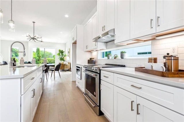 kitchen featuring decorative light fixtures, stainless steel appliances, white cabinetry, and sink