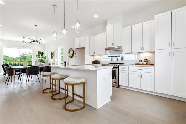 kitchen featuring white cabinets, ceiling fan, and an island with sink