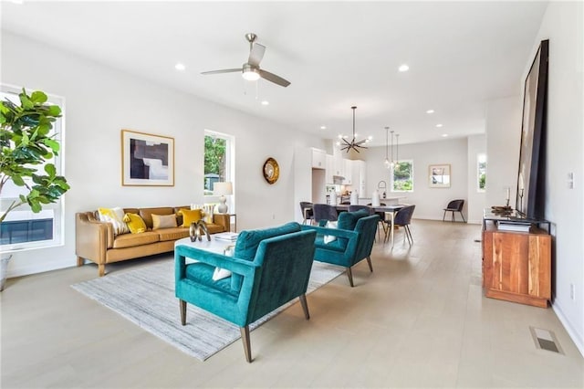 living room featuring ceiling fan with notable chandelier