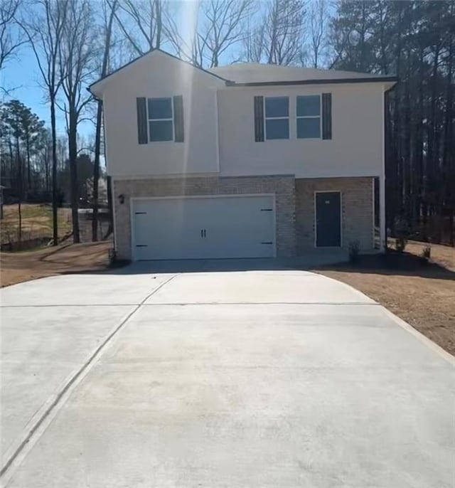 view of front facade with stucco siding, an attached garage, and driveway