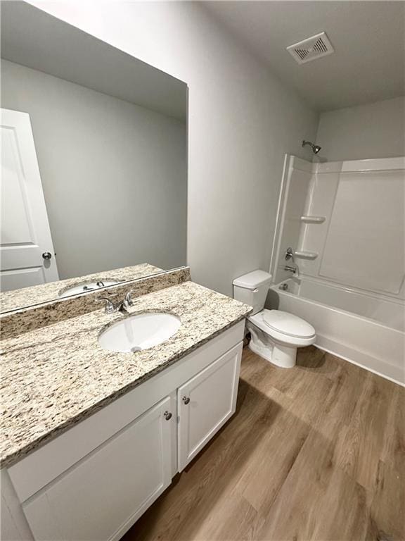 full bath featuring visible vents, toilet, shower / bathing tub combination, wood finished floors, and vanity