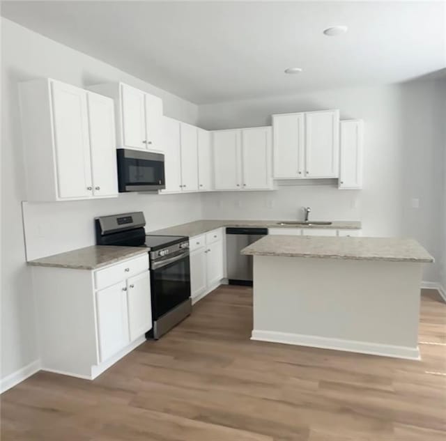 kitchen with a sink, light wood-type flooring, appliances with stainless steel finishes, and white cabinetry