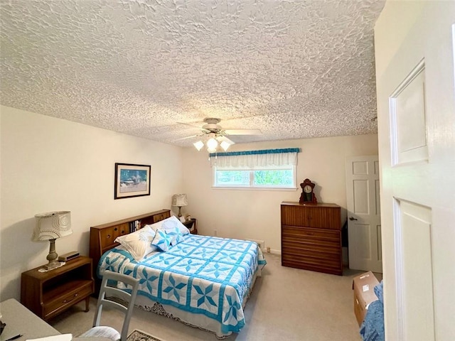 bedroom with ceiling fan, light carpet, and a textured ceiling