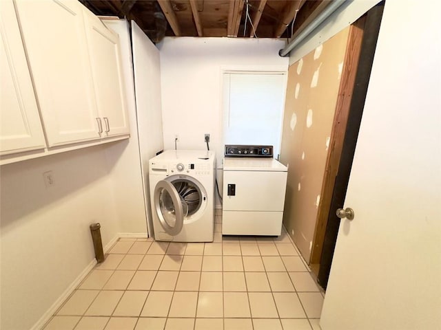 clothes washing area with cabinets, washer and dryer, and light tile patterned floors