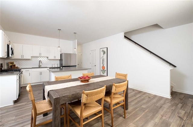 dining area featuring light wood-style flooring, stairway, and baseboards
