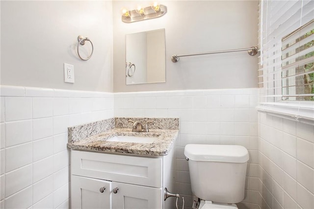 bathroom with tile walls, vanity, and toilet