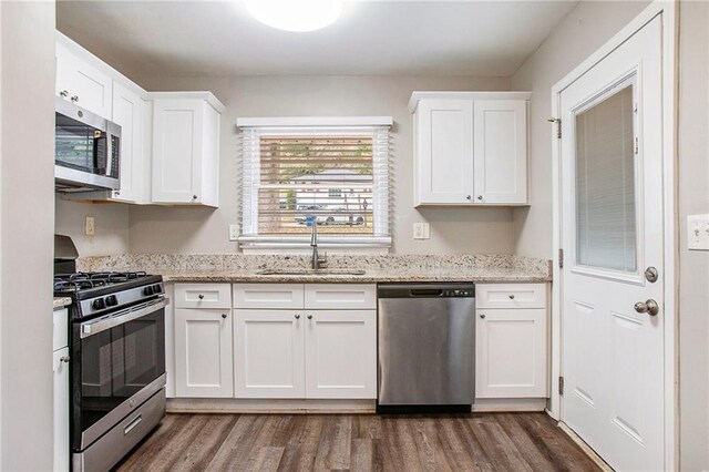 kitchen featuring dark wood-type flooring, sink, light stone countertops, white cabinetry, and appliances with stainless steel finishes