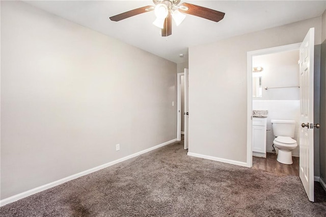 unfurnished bedroom with connected bathroom, dark carpet, and ceiling fan