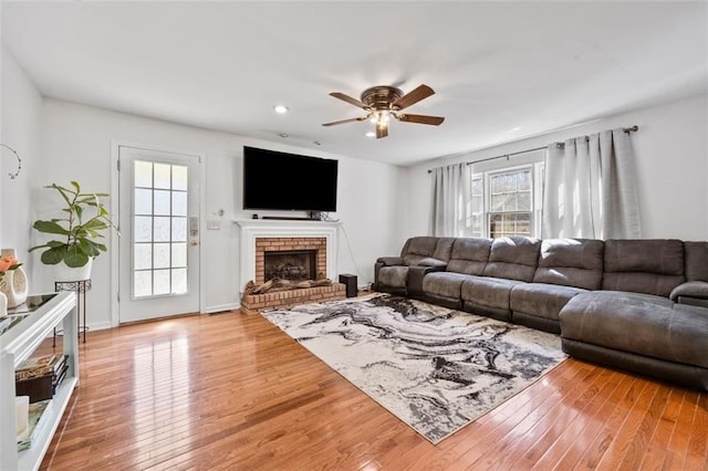 living room featuring a ceiling fan, recessed lighting, a fireplace, and light wood-style floors